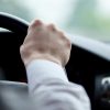 man driving a car with his hands on the steering wheel