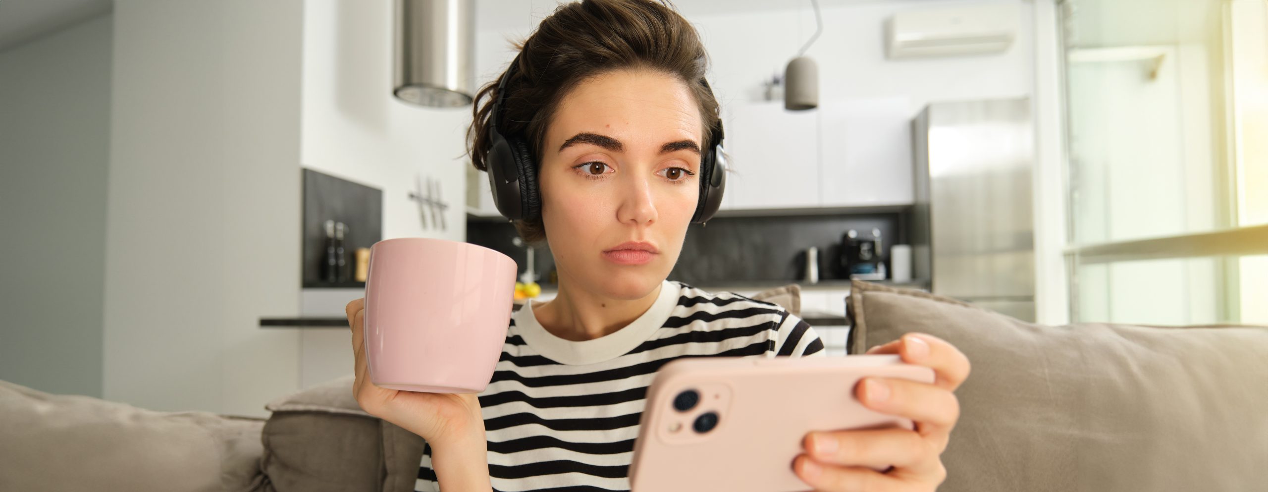 Cât de multe date mobile consumă TikTok, YouTube și Netflix? 1 portrait woman with scared concerned face watching video smartphone drinking tea wearing scaled